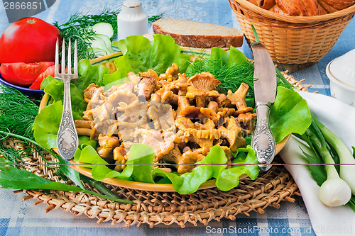 Image of Fried mushrooms of chanterelle on a dish together with lettuce l