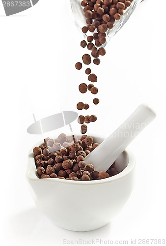 Image of Black aromatic peppercorns falling into mortar and pestle