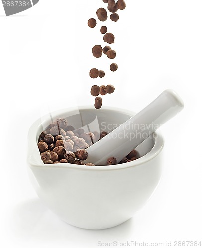 Image of Black aromatic peppercorns falling into mortar and pestle