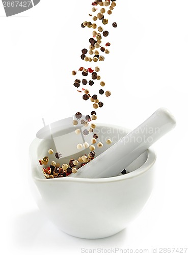 Image of various peppercorns falling into mortar and pestle