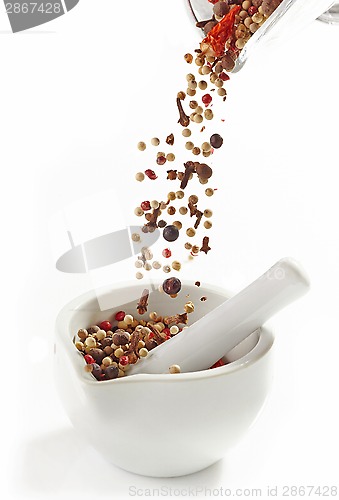 Image of various spices falling into mortar and pestle