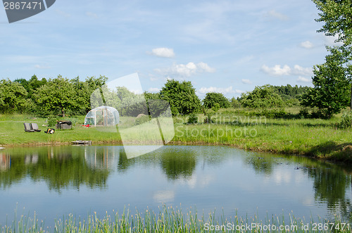 Image of village pond greenhouse in summer 