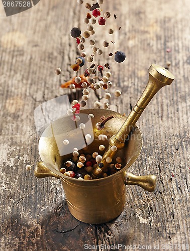 Image of various spices falling into mortar and pestle