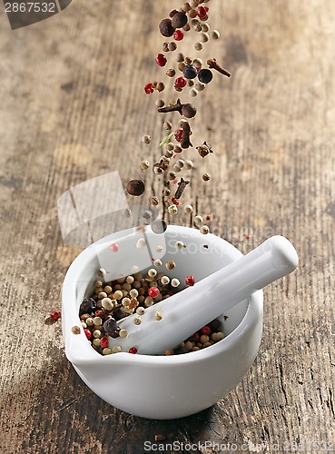 Image of various spices falling into mortar and pestle