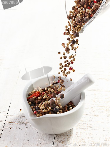 Image of various spices falling into mortar and pestle