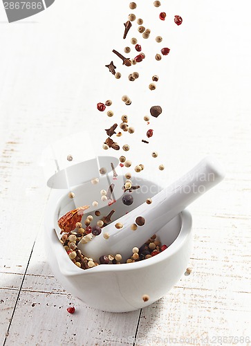 Image of various spices falling into mortar and pestle