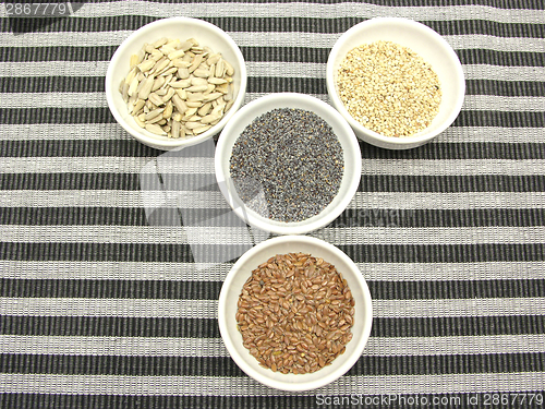 Image of Four bowl with different seeds on a striped background