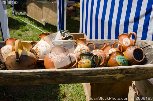 Image of clay jugs lying in wooden trough at village market 