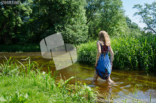 Image of blonde girl blue mottled dress wade flowing river  