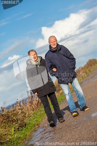 Image of happy elderly senior couple walking on beach