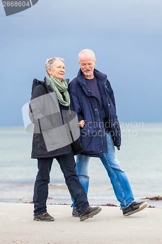 Image of happy elderly senior couple walking on beach