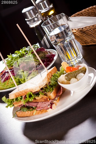 Image of Delicious pastrami club sandwich and pickles