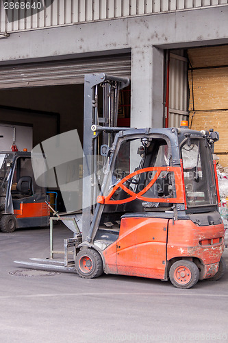 Image of Small orange forklift parked at a warehouse