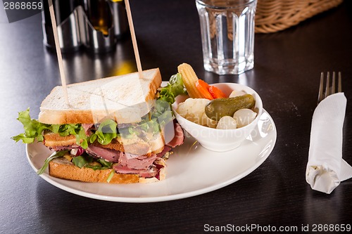 Image of Delicious pastrami club sandwich and pickles