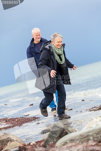 Image of happy elderly senior couple walking on beach