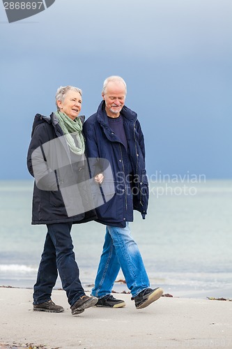 Image of happy elderly senior couple walking on beach