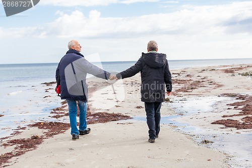 Image of happy elderly senior couple walking on beach