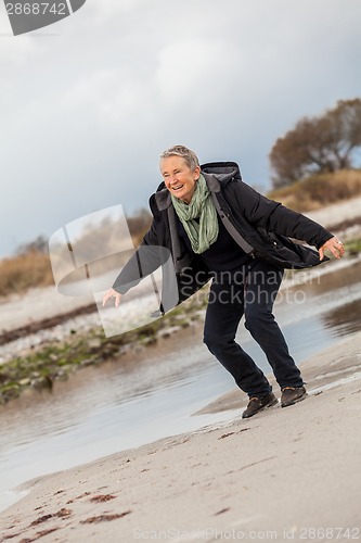 Image of Happy senior woman frolicking on the beach