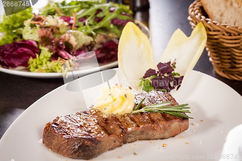 Image of Grilled beef steak topped with butter and rosemary