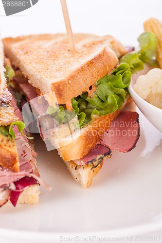 Image of Delicious pastrami club sandwich and pickles