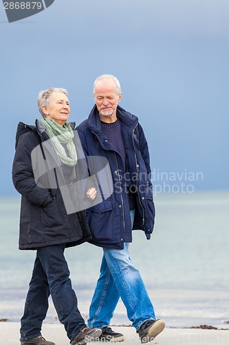 Image of happy elderly senior couple walking on beach