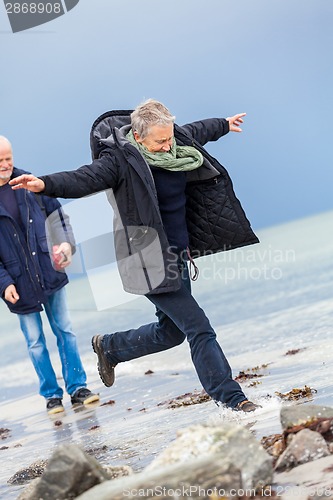 Image of happy elderly senior couple walking on beach