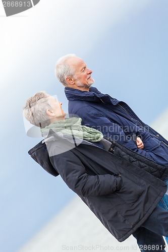 Image of happy elderly senior couple walking on beach