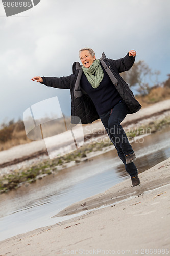 Image of Happy senior woman frolicking on the beach