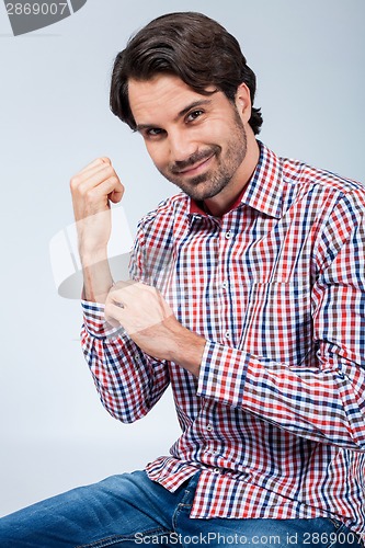 Image of Handsome young man sitting on a wooden box