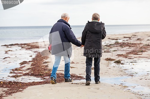 Image of happy elderly senior couple walking on beach