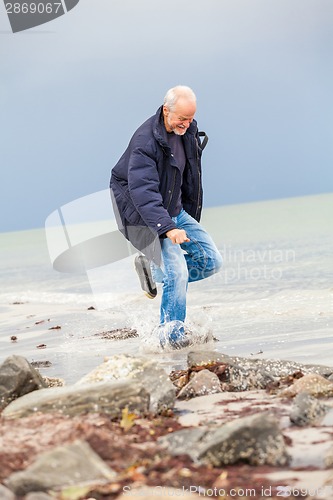 Image of happy elderly senior couple walking on beach