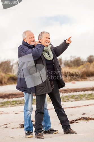 Image of happy elderly senior couple walking on beach