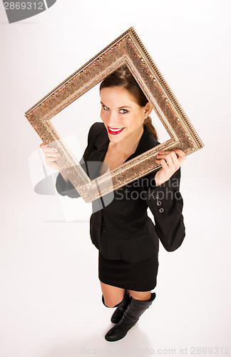 Image of Brunette Woman in Business Suit and Boots Holds Ornate Frame Ove