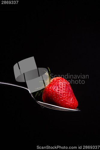 Image of Red Raw Food Strawberry on a Silver Spoon on Black Background