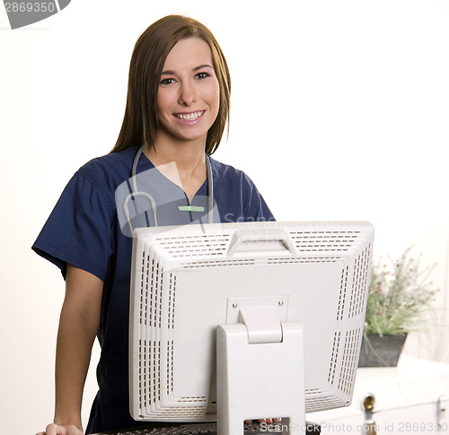 Image of Working Nurse Smiles Looking over Monitor at Computer Workstatio