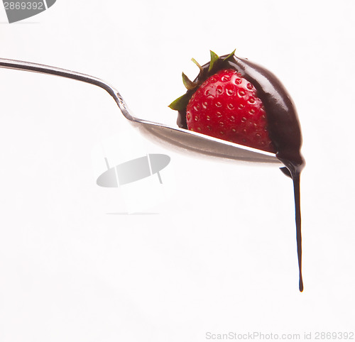 Image of sweet fruit strawberry in chocolate syrup on silver spoon