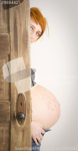 Image of Pregnant Woman Emerges From Behind Wooden Door