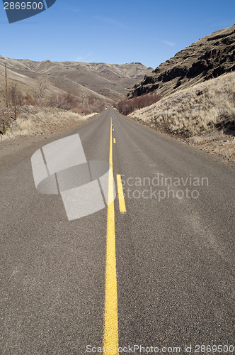 Image of Lonely Two Lane Divided Highway Cuts Through Dry Hills Landscape