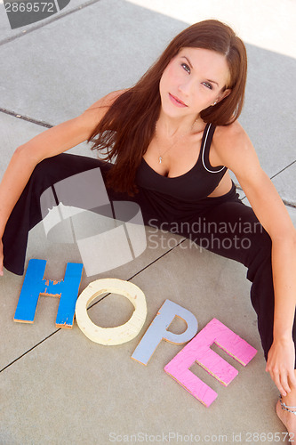 Image of Hope Communicated in Block Letters on Cement By Attractive Woman