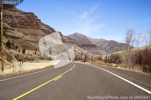 Image of Lonely Two Lane Divided Highway Cuts Through Dry Mountainous Lan