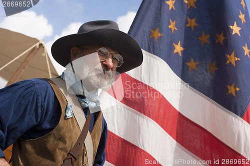 Image of Civil War Re-enactment Scout Stands By Flag In Army Camp