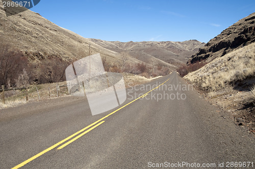 Image of Lonely Tow Lane Divided Highway Cuts Through Dry Hills Landscape