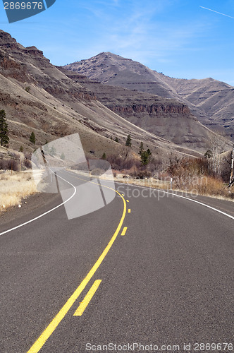Image of Lonely Two Lane Divided Highway Cuts Through Dry Mountainous Lan