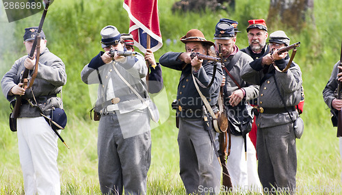 Image of Civil War Re-enactment Confederate Soldiers Fire Rifles During B