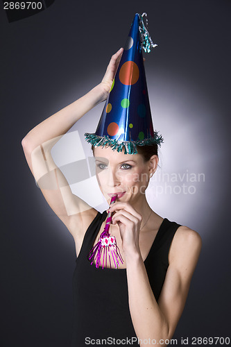 Image of Party Girl Wears Decorated Hat Blowing Noise Maker