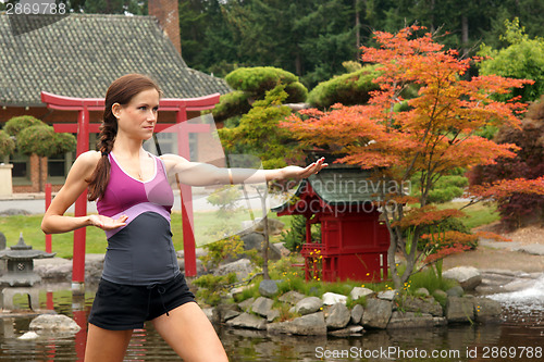 Image of Fit Woman in Fighting Pose Near Yoga Pond Outside