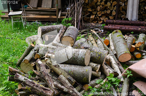 Image of pile of chopped logs branche to woodshed in garden 