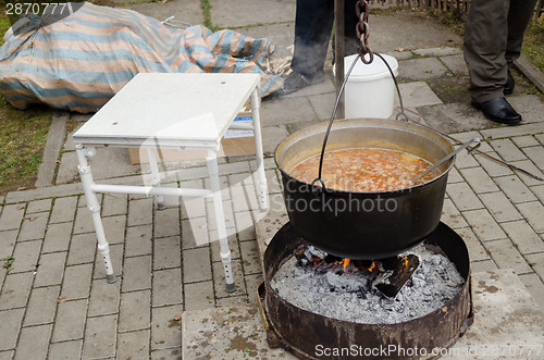 Image of black pot full of rustic soup on open fire outdoor 