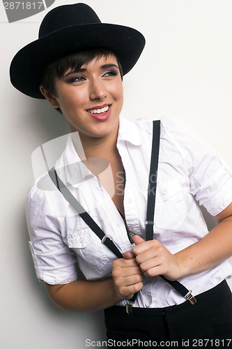 Image of Young Androgynous Woman Stands Wearing Hat Suspenders White Back