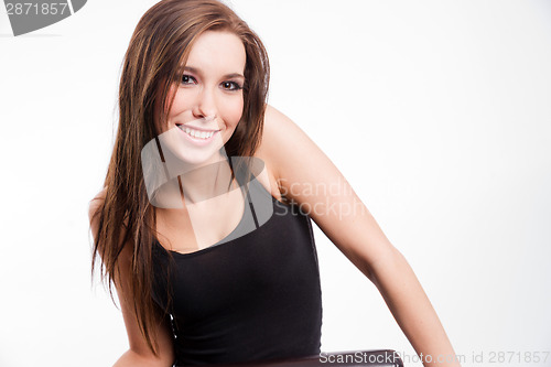 Image of Young woman straddling common chair looking happy